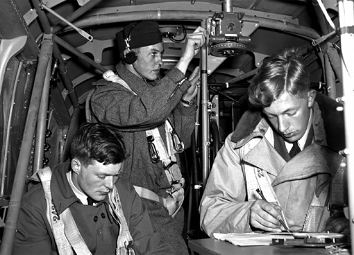 arms_air_training_prog_6 Sgt E.M. Romilly, RCAF, W.H. Betts, RAAF, and J.A. Mahoud, RAF, practicing navigation techniques on board an Anson from the No 1 Air Navigation School, Rivers, Manitoba, 4th June, 1941.
