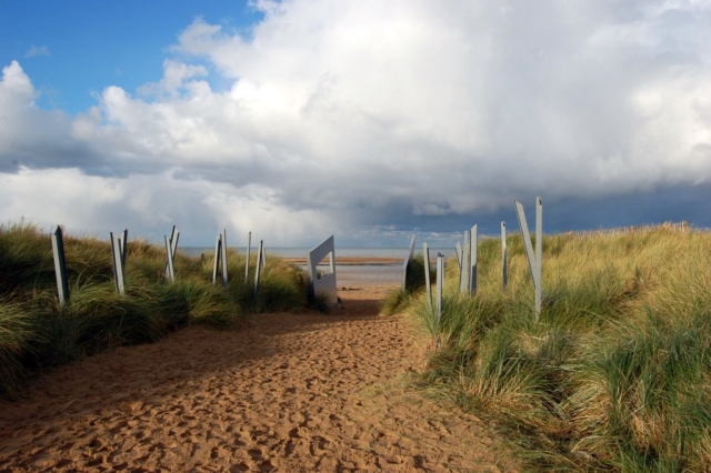 Entrance to Juno Beach ©CJB Colour photo. Metal spikes and walls line a well-trodden path towards Juno Beach.
