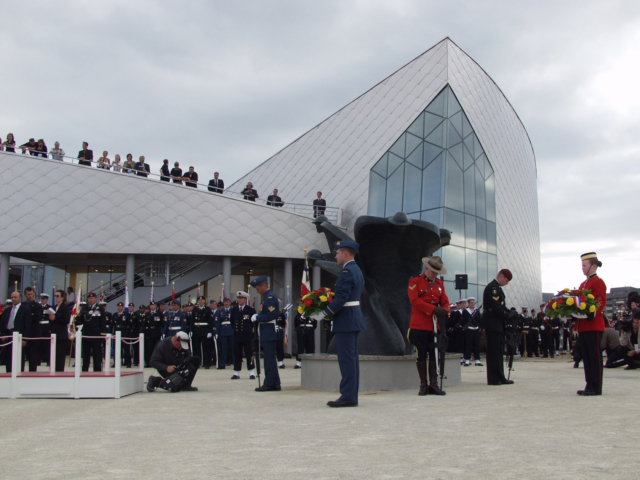 JBC Opening Colour photo. People in uniform stand at attention in front of the Juno Beach Centre.