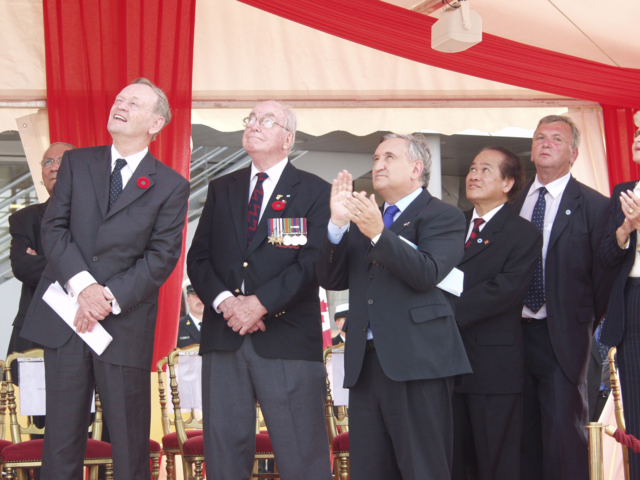 Prime Minister Jean Chretien and JBC co-founder Garth Webb Colour photo. A group of men in suits look upwards.